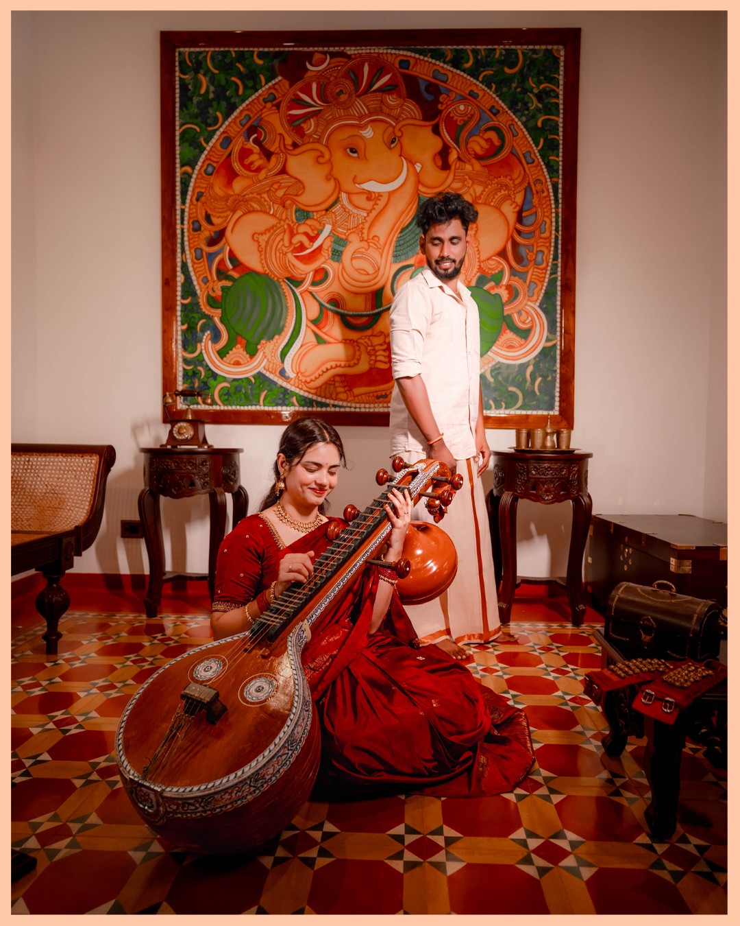 Sneha and Deepak seeking divine blessings before antique Ganesha wall mural with veena at Kurumboor Mana Palace