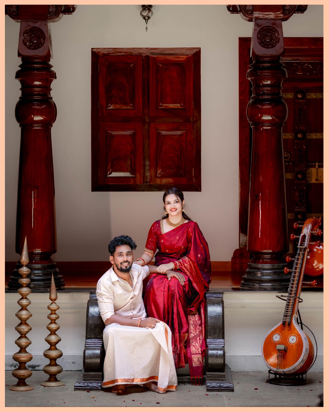 Royal heritage portraits framed by carved teakwood pillars and classical veena at Kurumboor Mana