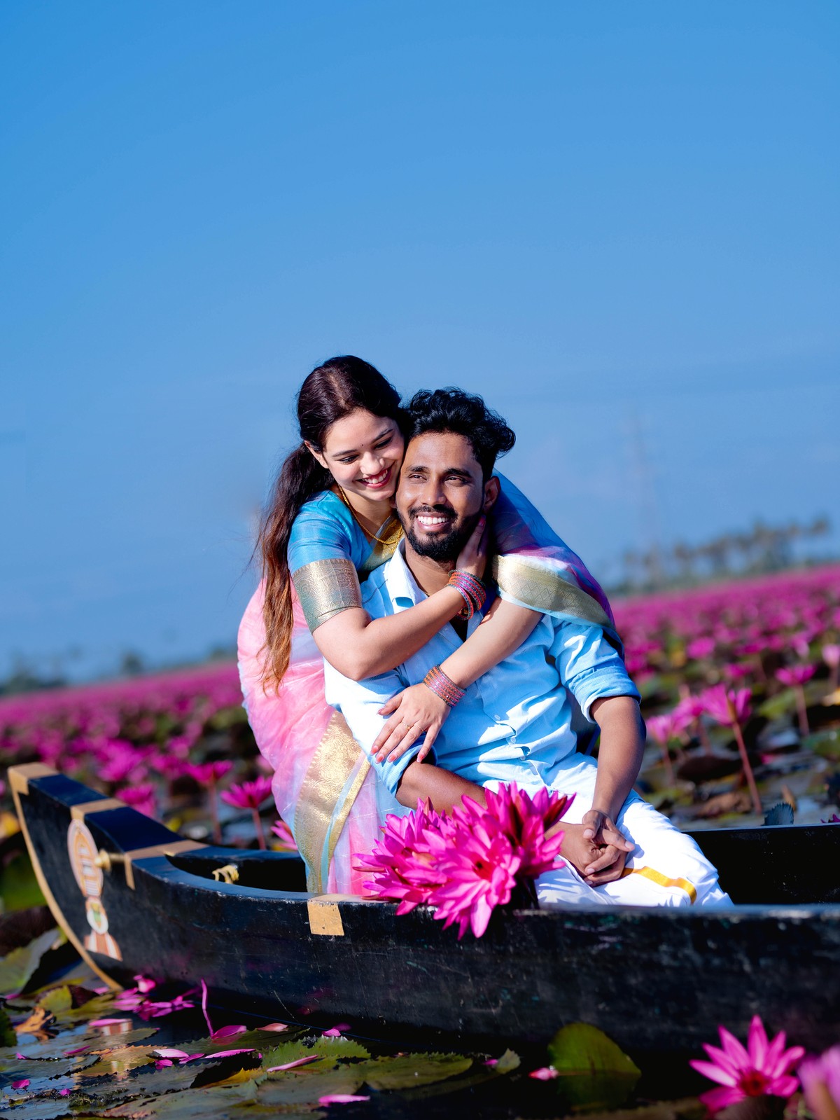 Candid romantic back hug of Shneka embracing Deepak on country boat at Malarikal water lily fields by AK Photography