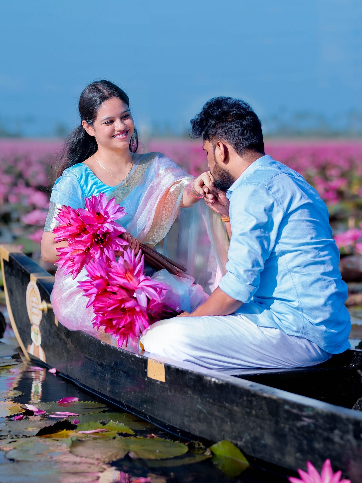 Tender hand kiss romantic pre-wedding portrait of Deepak and Shneka on country canoe in Malarikal water lily lake